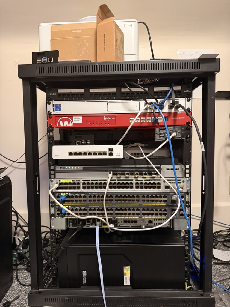 Paul's homelab rack — WatchGuard firewall, Cisco Catalyst switches, patch panel, and UPS